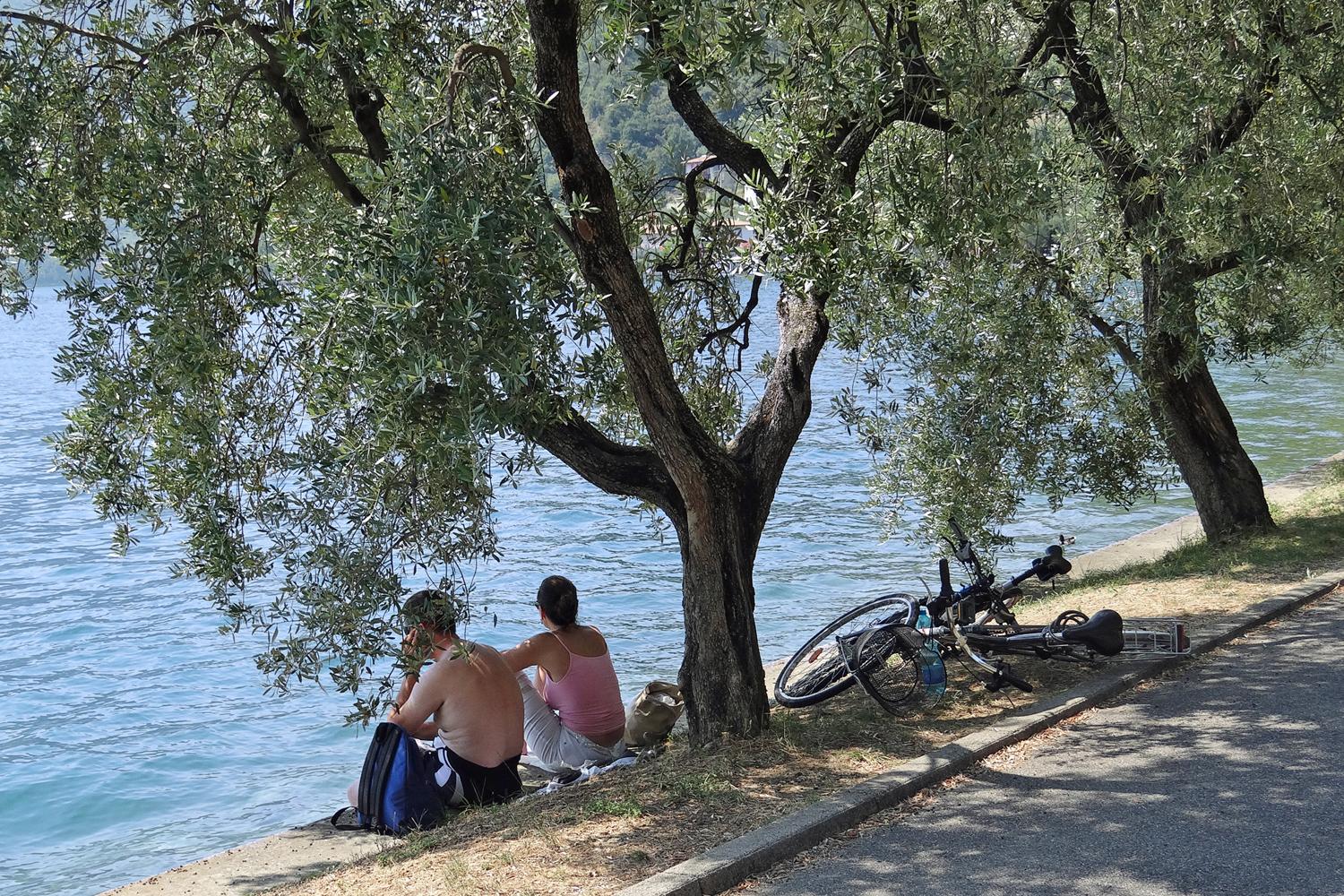 Ein Paar macht eine Auszeit am Ufer des Sees, ihre Fahrräder liegen daneben im Gras