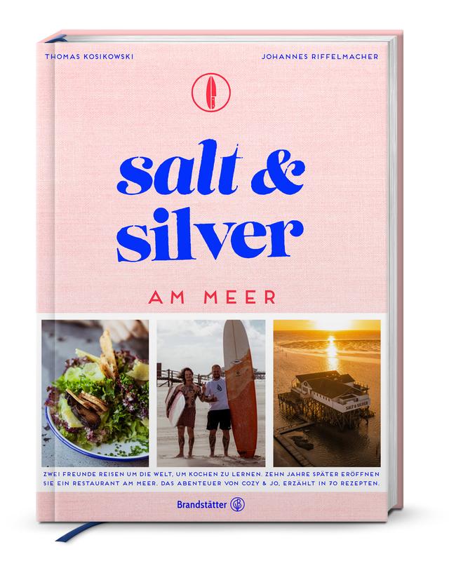 Rosa Kochbuch mit dem Titel salt and silver am Meer, darauf sind drei Fotos zu sehen.